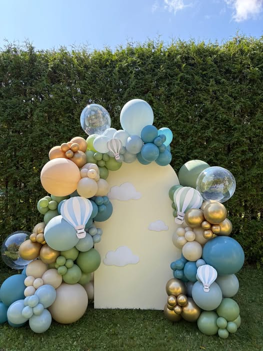 Arche de ballons sur le thème des montgolfières dans les tons de bleu pâle, eucalyptus et doré